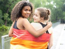 Two lesbian people friendship with rainbow pride flag. Cheerful gay person having fun together with equality respect to love and freedom lifestyle. Diversity of young homosexual couple, LGBTQ rights. photo