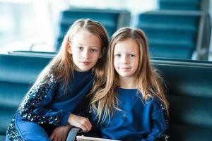 Little adorable girls in airport waiting for boarding near big window photo