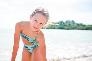 Adorable happy little girl on white beach photo