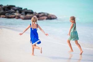 Little happy funny girls have a lot of fun at tropical beach playing together. photo