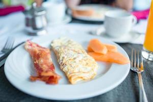 Healthy tasty american breakfast with omlette and bacon on table in cafe photo