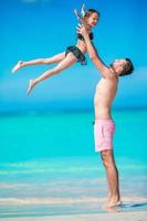 Little girl and happy dad having fun during beach vacation photo