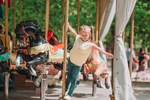 Adorable little girl near the carousel outdoors photo