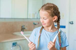 Little beautiful girl with white teeth and her young father brushing teeth in the bathroom photo