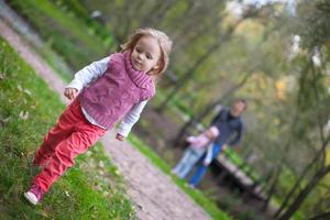 Portrait of little girl close-up and her father and sister in the background photo