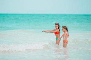 Little girls having fun at tropical beach playing together at shallow water photo