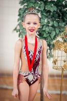 hermosa pequeña gimnasta entrenando en la alfombra y lista para las competiciones foto