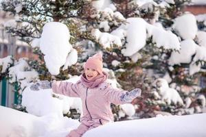 Adorable little happy girl sledding in winter snowy day. photo