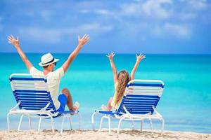 Father and daughter hands up on beach sitting on chaise-longue photo