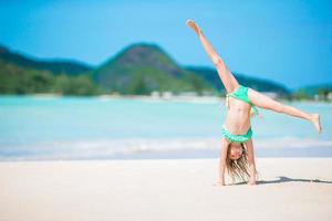 Active little girl at beach having a lot of fun. Cute kid making sporty exercises on the seashore photo