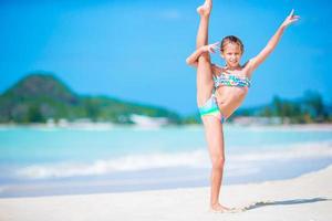 Beautiful little girl on beach having fun. Happy girl enjoy summer vacation background the blue sky and turquoise water in the sea on caribbean island photo