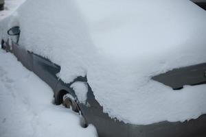 el coche está en la nieve. coche cubierto de nieve. transporte en ventisca. foto