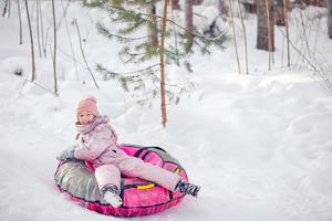 adorable niña feliz en trineo en invierno día de nieve. foto