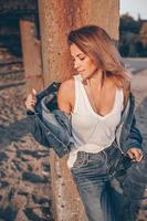 Outdoor fashion portrait of stylish girl wearing jeans jacket on the beach. photo
