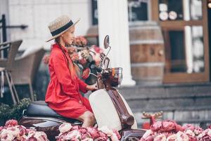 Adorable little girl in hat on the moped outdoors photo