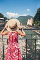 Little girl at hat on the embankment of a mountain river in a European city. photo