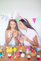 Mother and her little daughter painting eggs. Happy family preparing for Easter. photo