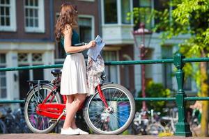 Happy young woman with a city map on bike in european city photo