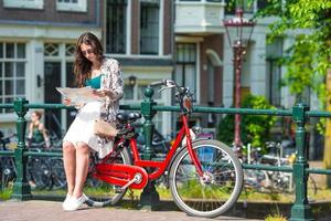 Happy young woman with city map and bikes in european city photo