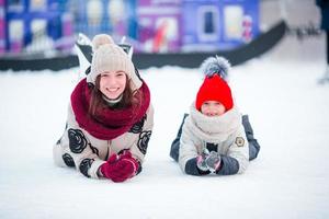 Little adorable girl with her mom skating on ice-rink photo