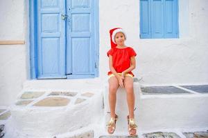 Little girl in santa hat outdoors in the city on Christmas vacation photo
