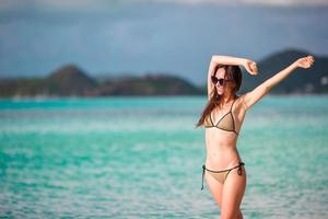 gente de vacaciones en la playa - mujer mirando el paraíso perfecto con agua turquesa del océano en vacaciones en el caribe. chica en bikini tomando el sol en viajes de vacaciones en la isla de lujo. foto