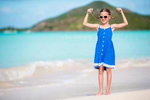 Beautiful little girl in dress at beach having fun. Funny girl enjoy summer vacation. photo