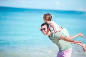 niña y papá feliz divirtiéndose durante las vacaciones en la playa foto