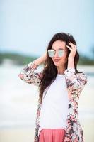 Young beautiful woman on white sand tropical beach. Caucasian girl in sunset photo