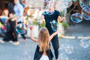 Adorable little girl blowing soap bubbles in Trastevere in Rome, Italy photo