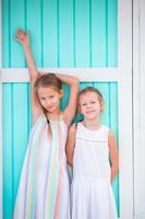 Adorable little girls on summer vacation background traditional colorful caribbean house photo