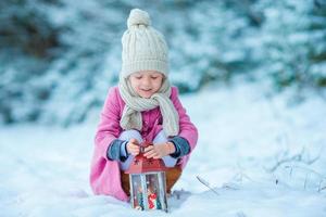 adorable niñita con un abrigo cálido al aire libre el día de navidad sosteniendo una linterna foto