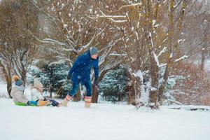 Little girls enjoying sledding in winter day. Family vacation on Christmas eve outdoors photo