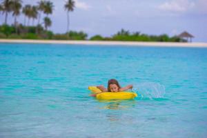 adorable niña en un colchón inflable de aire en el mar foto