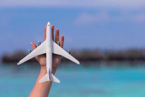 Little white toy airplane on background of turquoise sea photo