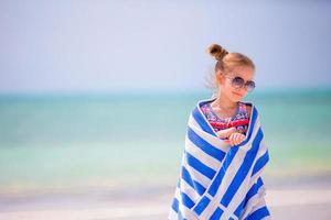 Adorable happy smiling little girl with towel on beach vacation photo