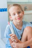 Little adorable girl brushes teeth in the bathroom photo