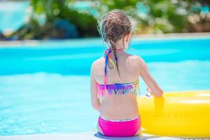Little active adorable girl in outdoor swimming pool ready to swim photo