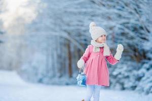 Adorable little girl wearing warm coat outdoors on Christmas day holding flashlight photo
