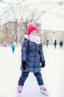 Adorable fashion little girl skating on the ice rink outdoors photo