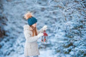 Adorable little girl wearing warm coat outdoors on Christmas day holding flashlight photo