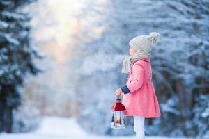 Adorable little girl wearing warm coat outdoors on Christmas day holding flashlight photo