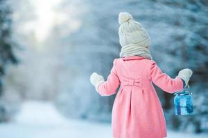 Little girl holding Christmas lantern outdoors on beautiful winter snow day photo