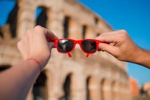 gafas de sol de primer plano en las manos frente al coliseo en roma, italia foto