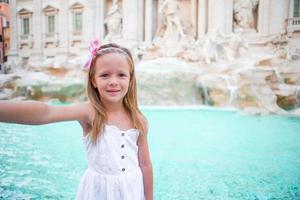 Adorable little girl taking selfie by the Fountain of Trevi in Rome. Happy kid enjoy her european vacation in Italy photo