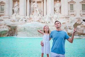 Happy family trowing coins at Trevi Fountain, Rome, Italy for good luck. Little girl and father making a wish to come back. photo