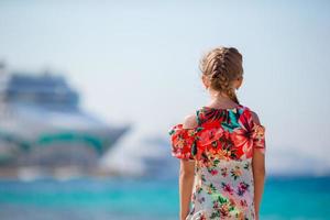 Adorable little girl at beach background big lainer in Greece photo