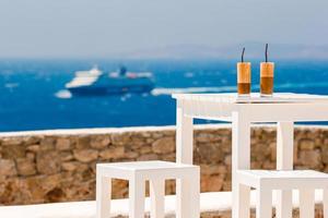 Frappe on the table background sea and big lainer. Summer iced coffee frappuccino, frappe or latte in a tall glass in beach bar photo