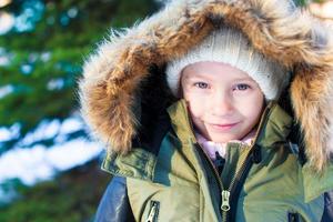 Portrait of little adorable girl with beautiful green eyes in snow sunny winter day photo