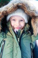 retrato de niña adorable con hermosos ojos verdes en la nieve soleado día de invierno foto